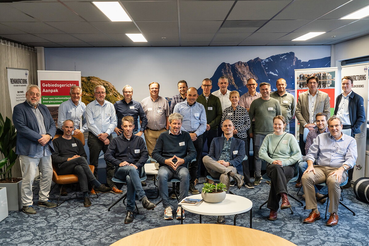Groepsfoto MEA deelnemers aan kennissessie 10 oktober 2024 bij Volvo. Op de foto staan 22 mensen waarbij een gedeelte naast elkaar staat en acht personen op een stoel zitten. Iedereen kijkt in de fotocamera.